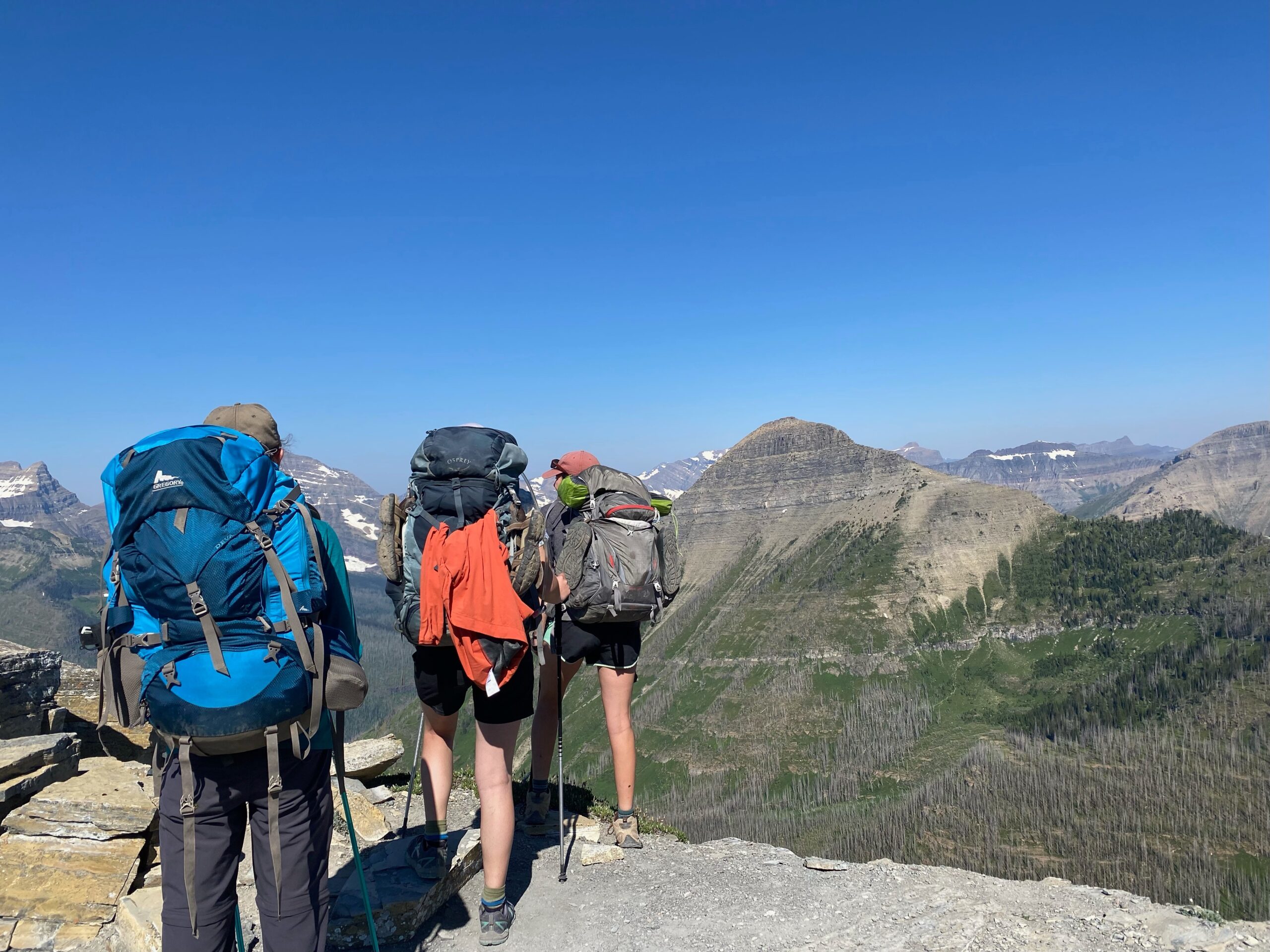 three backpackers on a hiking trail in Montana wilderness